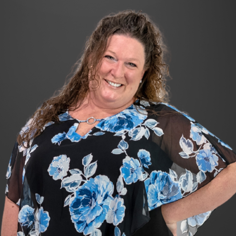 A closeup photo of Laura. She is wearing a black blouse with a blue flower pattern.