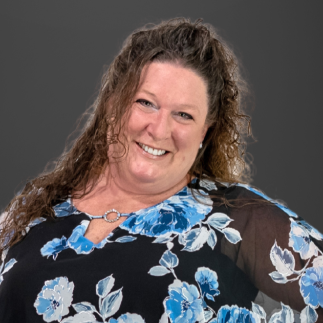 A closeup photo of Laura. She is wearing a black blouse with a blue flower pattern.